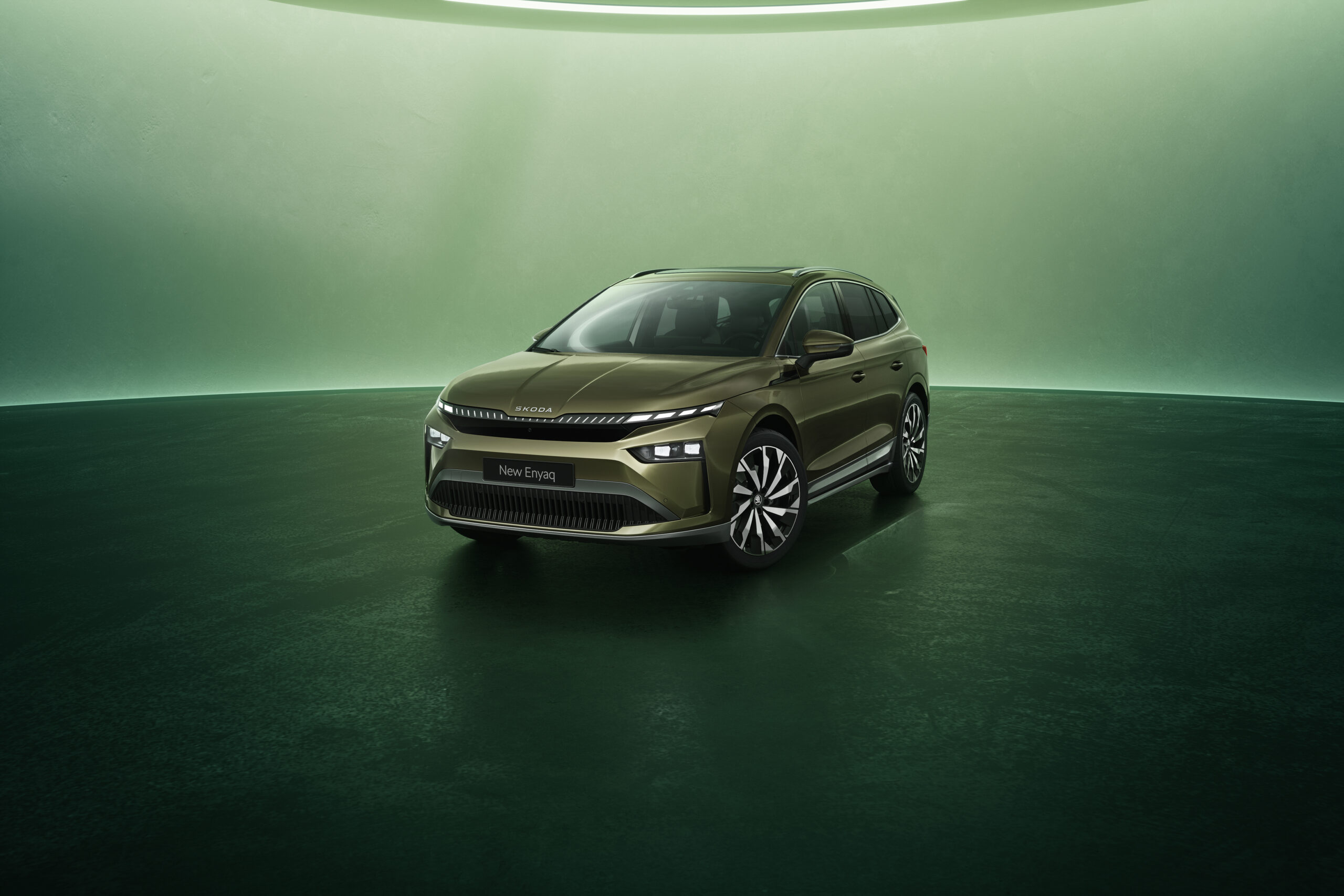 Auf dem Bild ist ein dunkelgrüner Skoda Enyaq zu sehen. Der Boden ist dunkelgrün und der Hintergrund ist hellgrün. Das bild wirkt etwas dunkel aber dennoch modern.