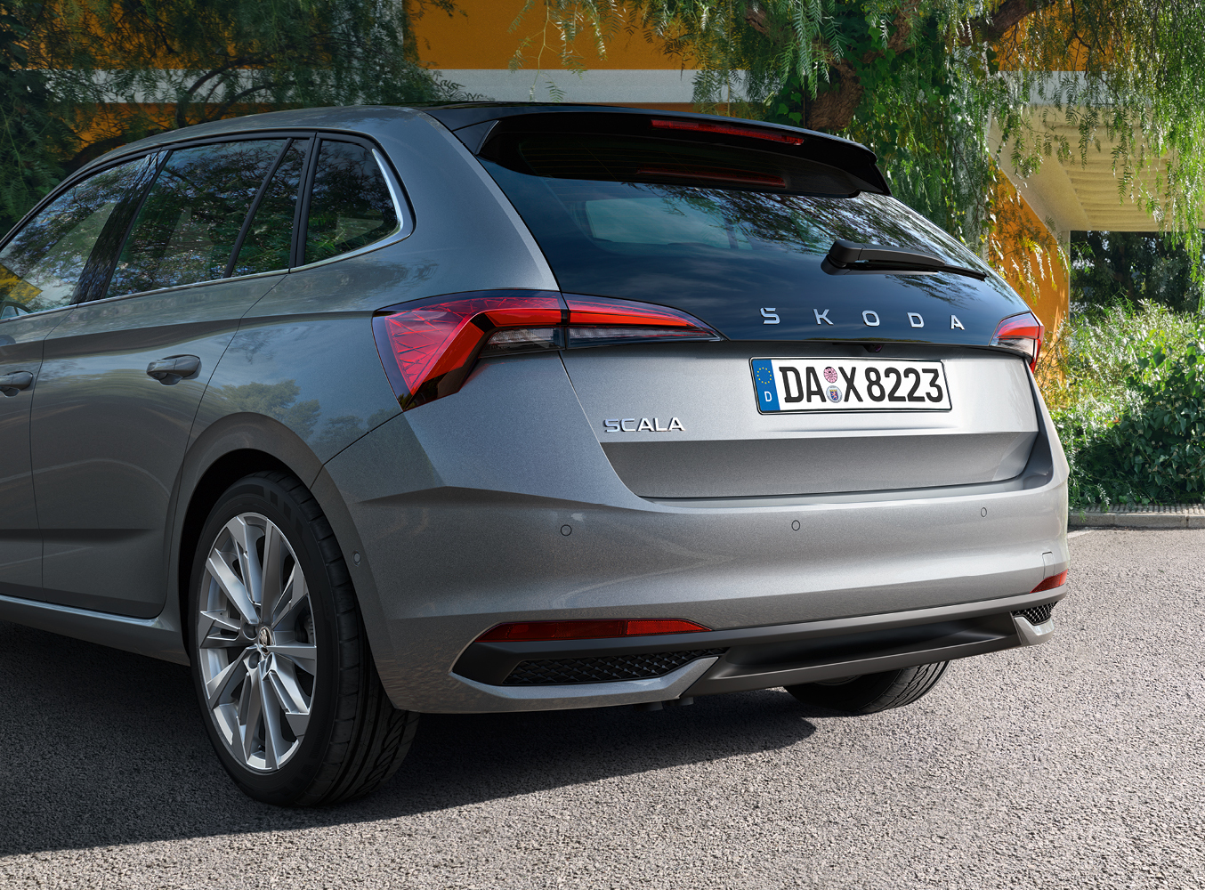 Auf dem Bild ist ein grauer Skoda Scala von hinten vor einem Haus zu sehen
