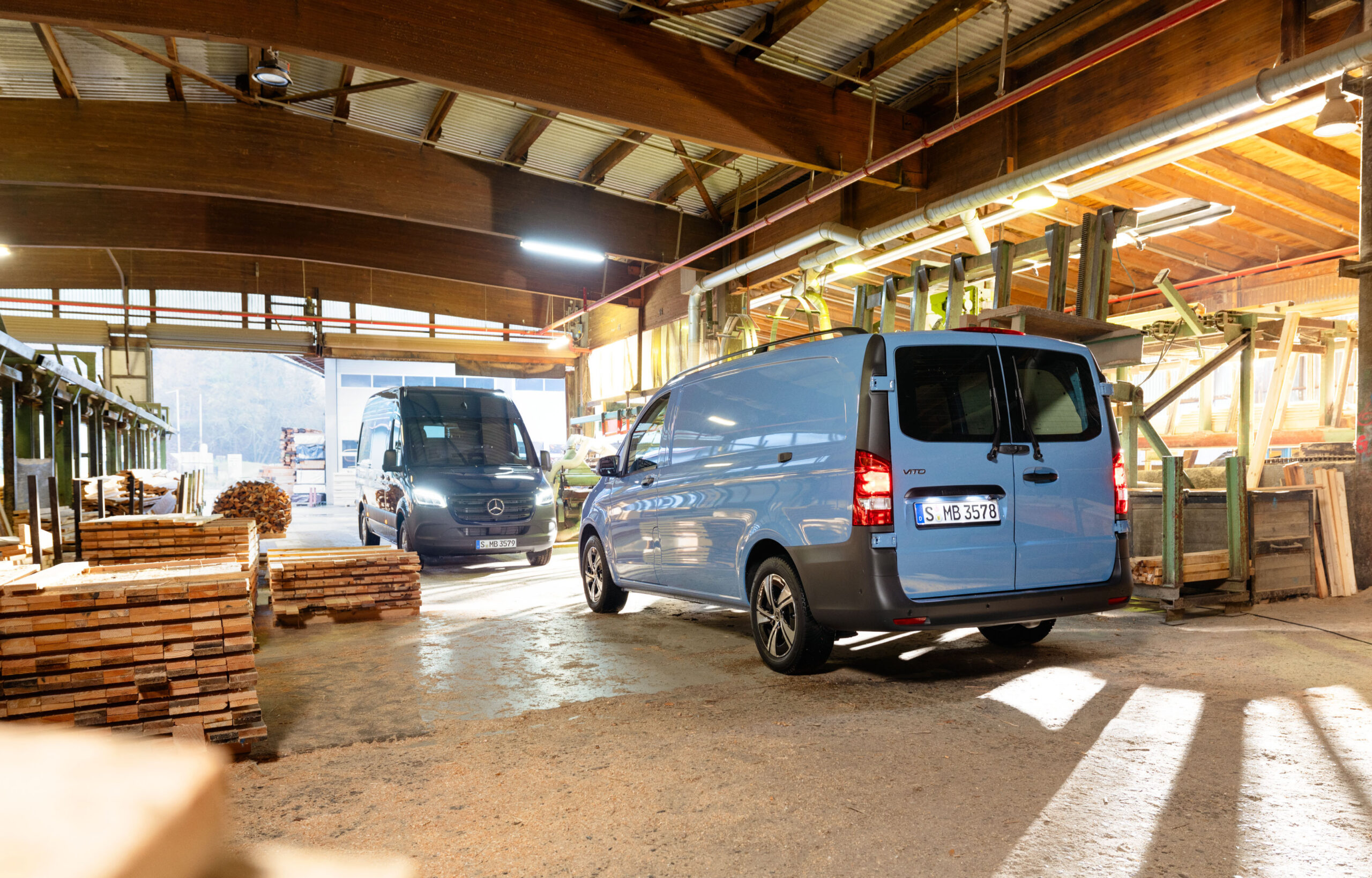 Auf dem Bild sind zwei Mercedes Nutzfahrzeuge zu sehen in einer Holzhalle